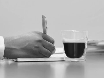 Notariusz pisze notatki w notesie i pije kawę